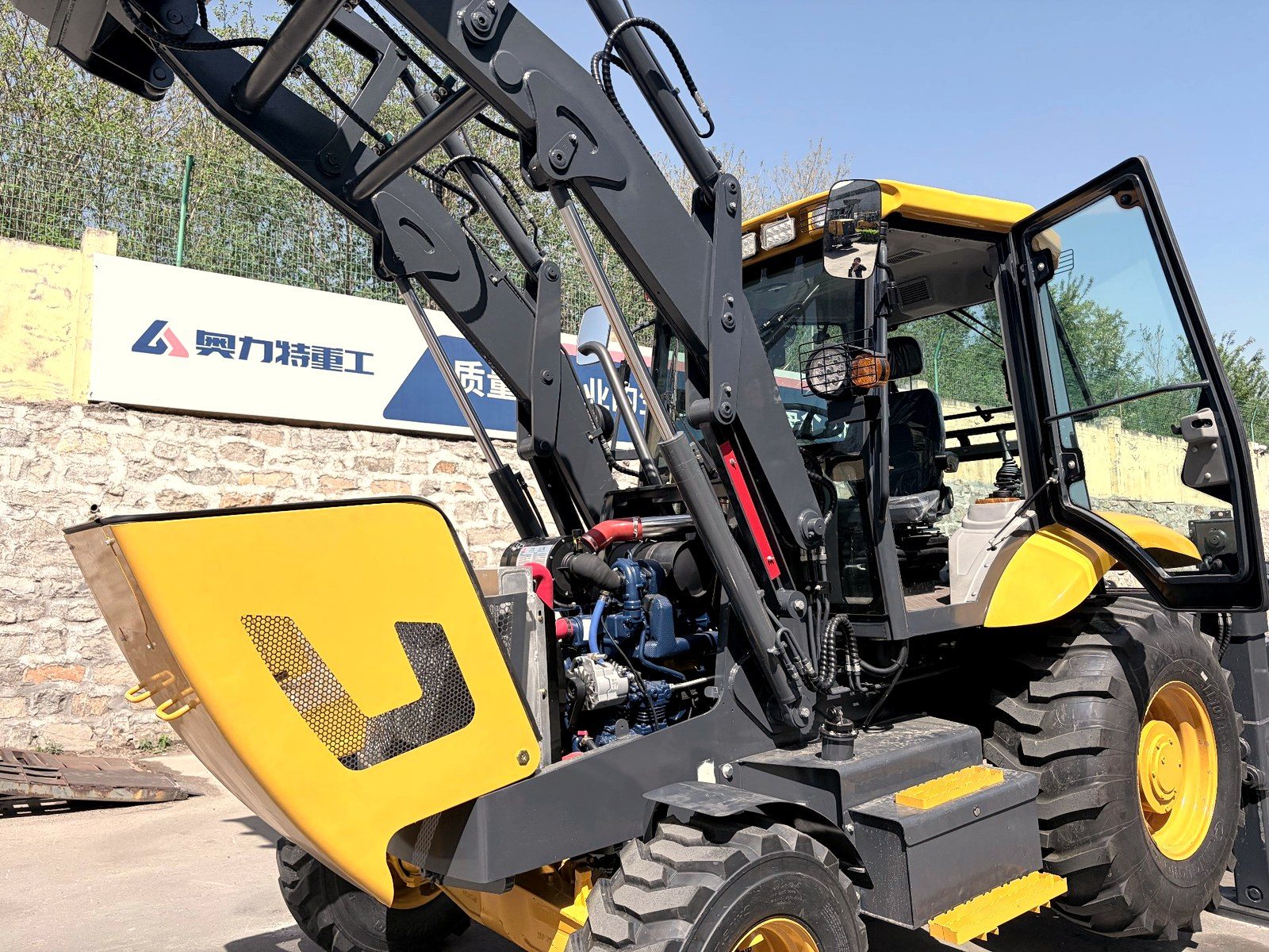 Open engine bay of a yellow backhoe loader showing engine and hydraulic components