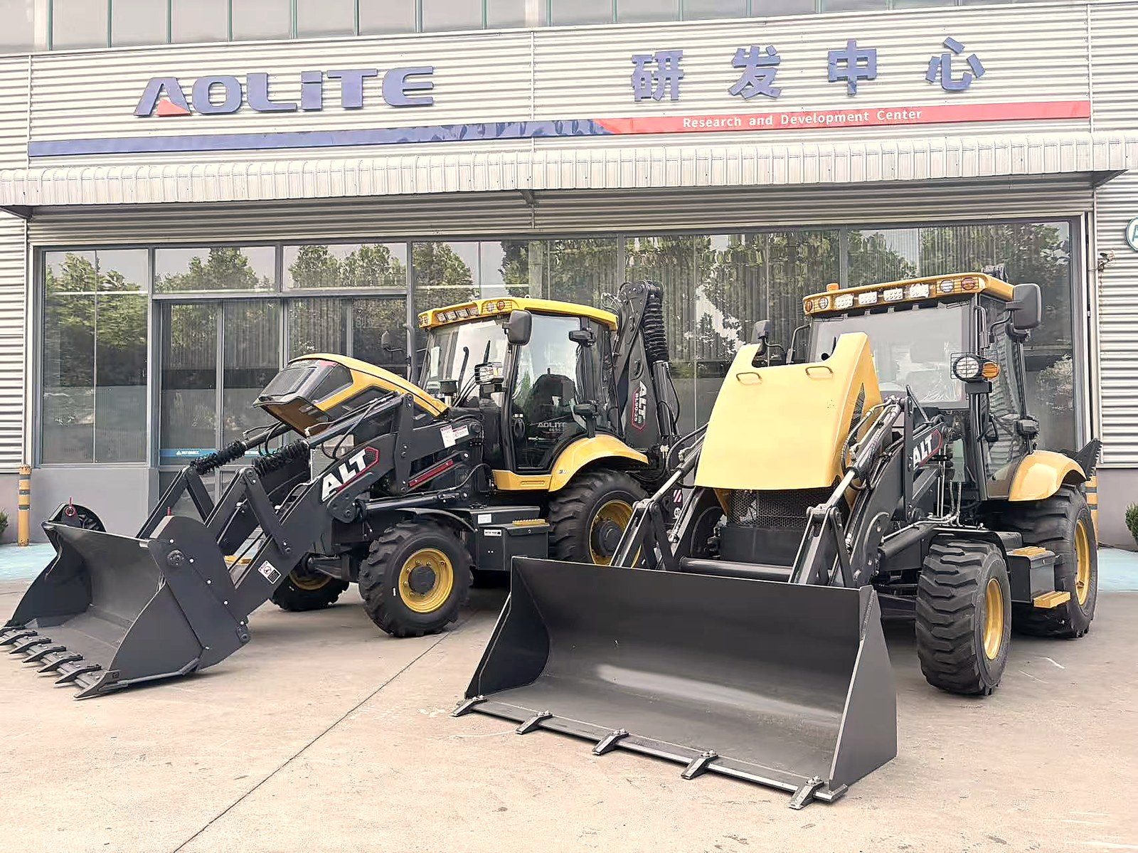 Two AOLITE backhoe loaders parked at the R&D Center — pre-delivery inspection