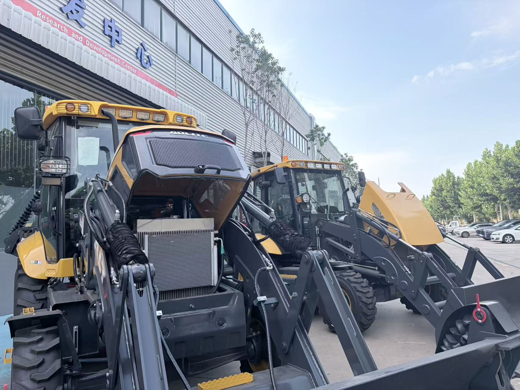 Backhoe loaders lined up at the R&D center — same platform, different configurations