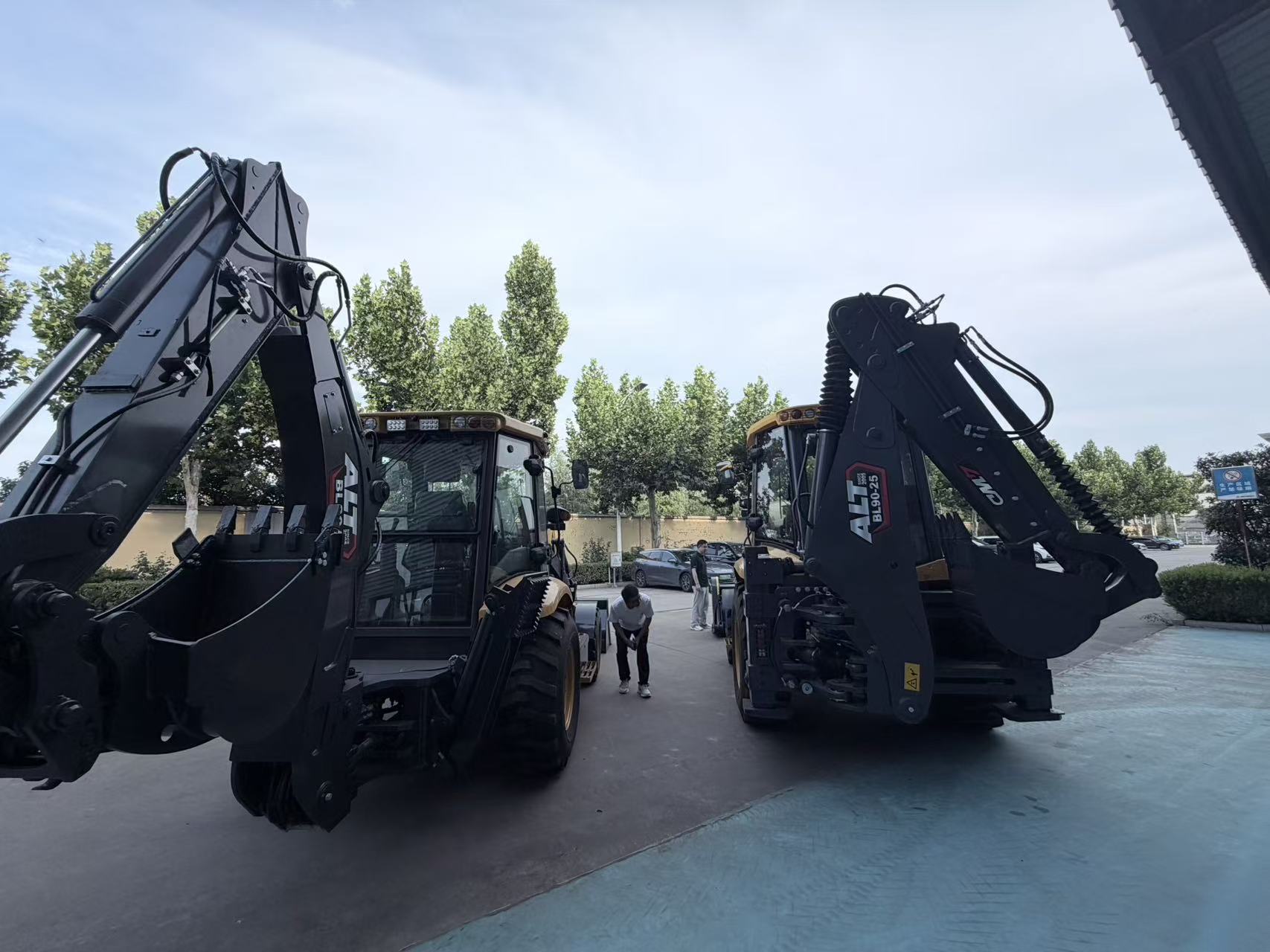 Two backhoe loaders of the same model side by side in the AOLITE yard