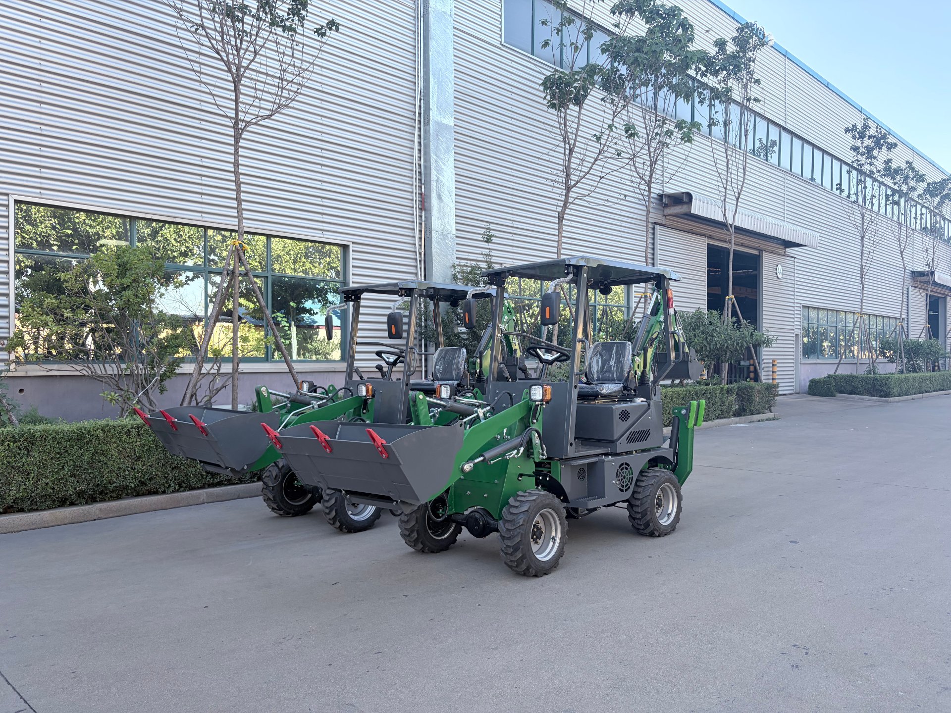 Two green AOLITE mini backhoe loaders side by side at the factory