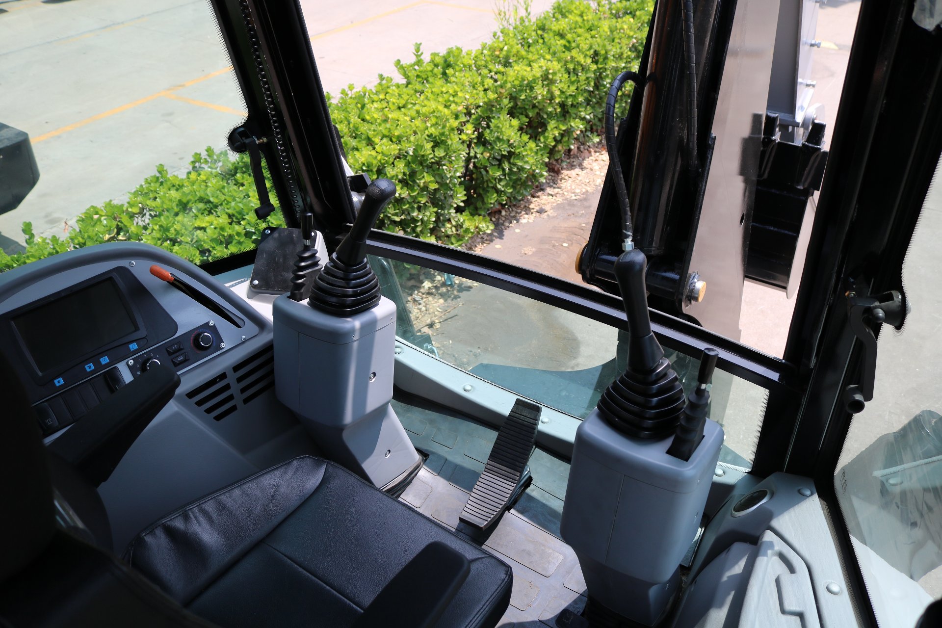 Backhoe loader cab interior showing joystick controls and the view through the window
