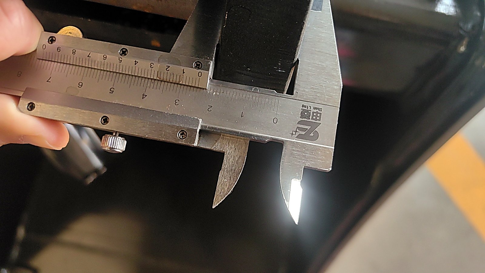 A vernier caliper measuring a machined pin during pre-shipment inspection at the AOLITE factory