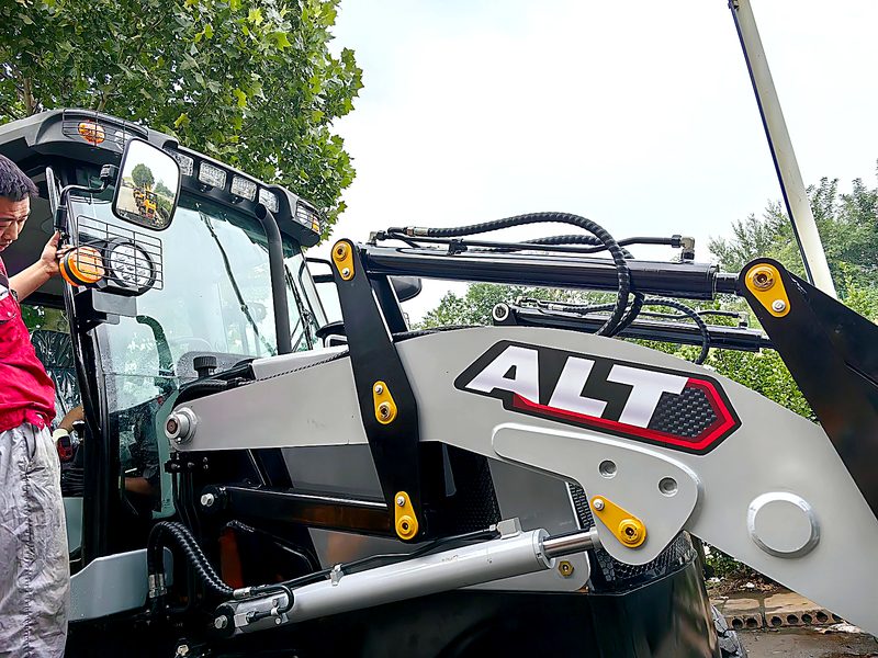 Mechanic inspecting the front loader linkage of an ALT backhoe