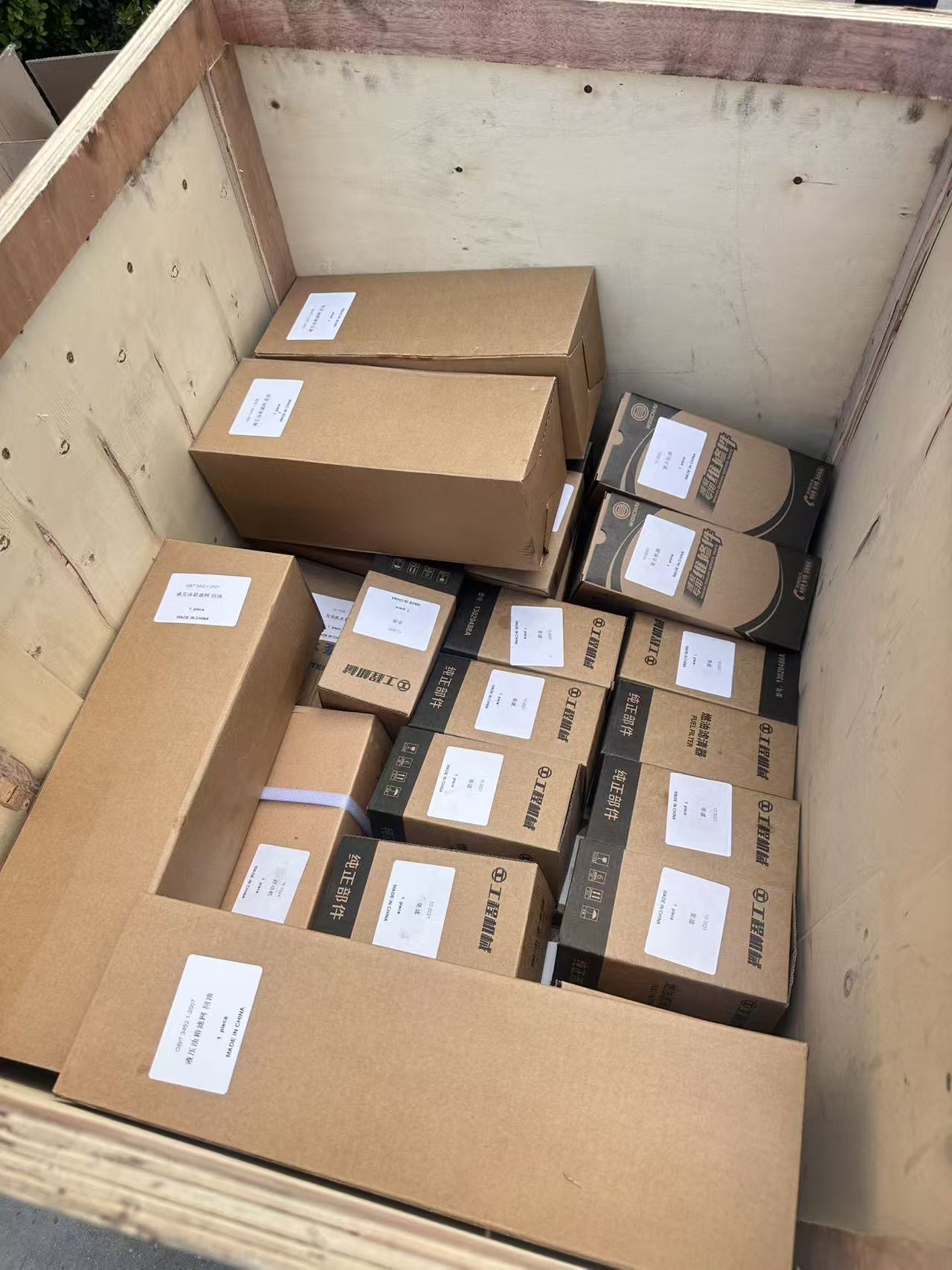 A packed wooden export crate filled with labelled backhoe loader spare part boxes ready to ship with the machine