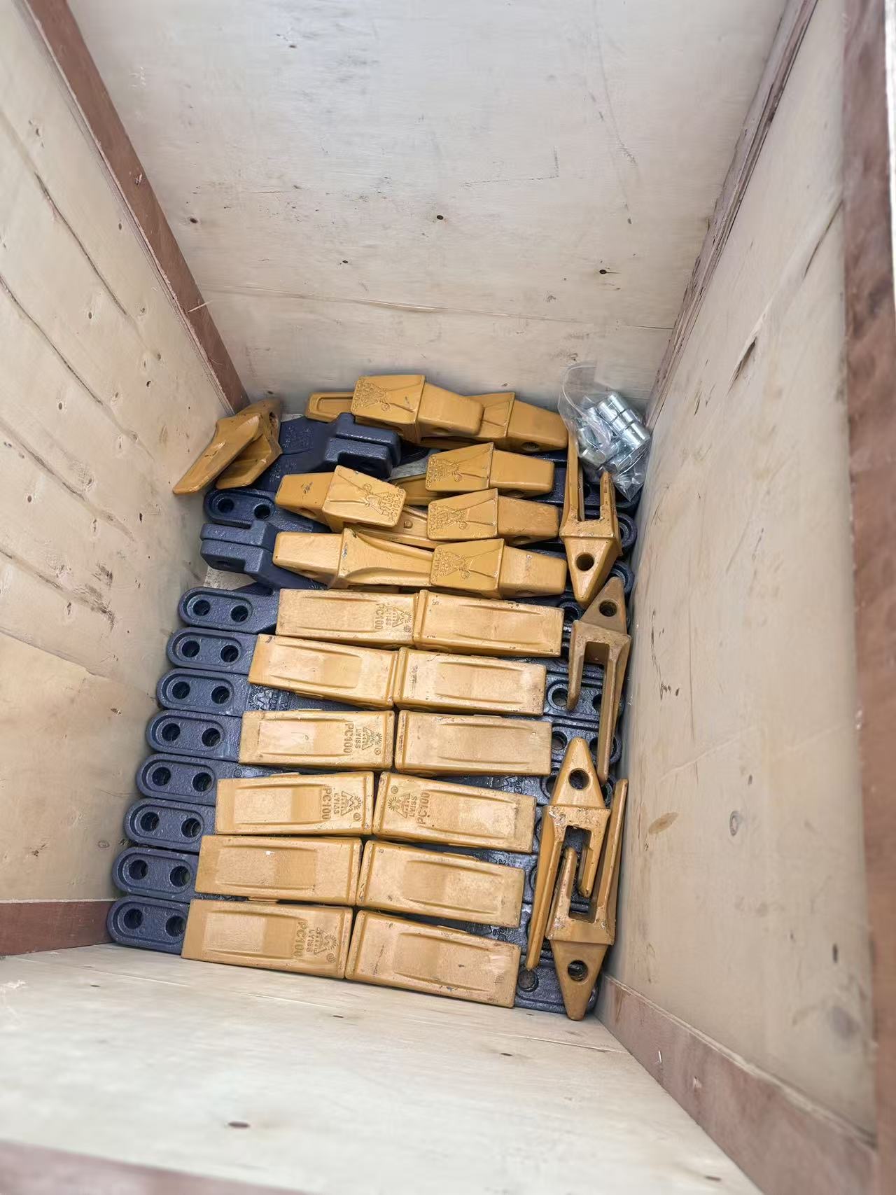 A wooden crate filled with backhoe loader bucket teeth and retaining bolts packed for export