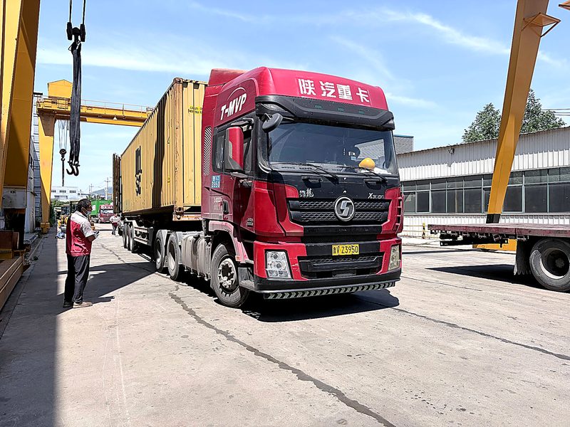 Shacman container truck waiting at the loading bay — backhoe loader
