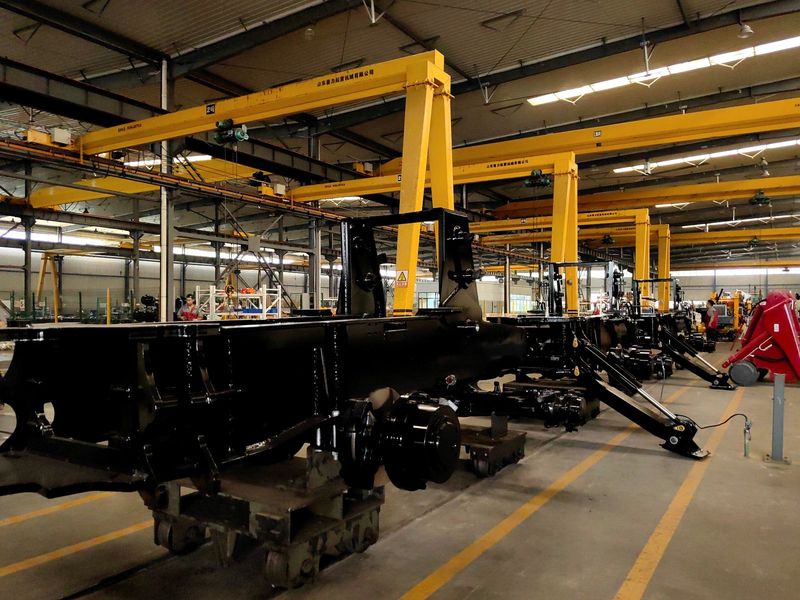 Multiple backhoe loader frames lined up in the workshop