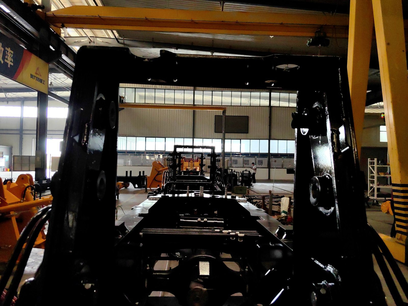 A backhoe loader chassis under construction on the AOLITE assembly floor, seen from inside the frame